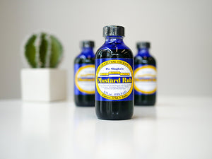 Image of 3 bottles of Dr. Singha's Mustard Rub on a white table with a small cactus in the background